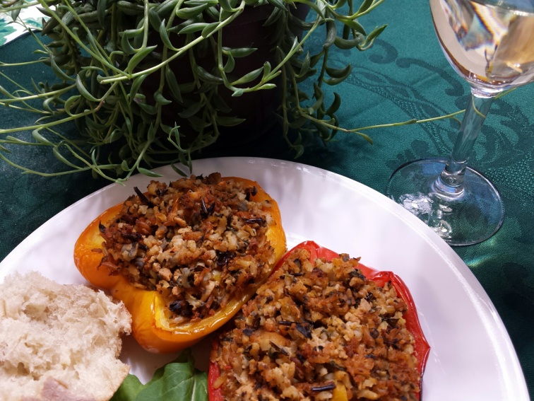 savory stuffed peppers on a plate with a hunk of crusty bread and a glass of wine